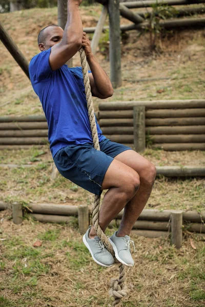 Hombre en forma escalando una cuerda durante la carrera de obstáculos — Foto de Stock