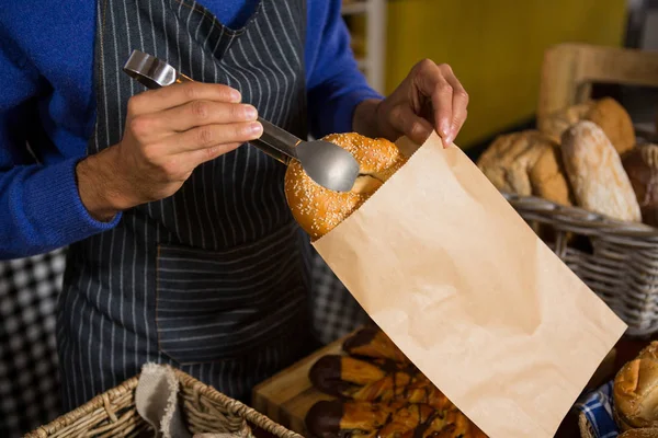 Középső szakasz csomagolás croissant papírzacskóban pultnál a személyzet — Stock Fotó