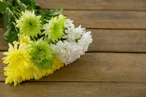 Bunch of yellow flowers on wooden plank — Stock Photo, Image