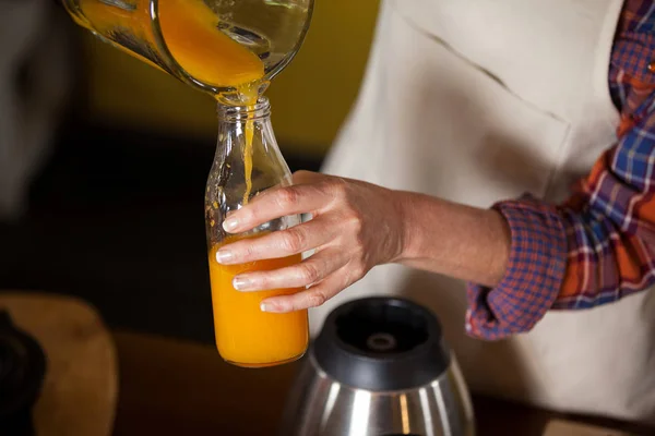 Female staff pouring juice in a bottle — Stock Photo, Image