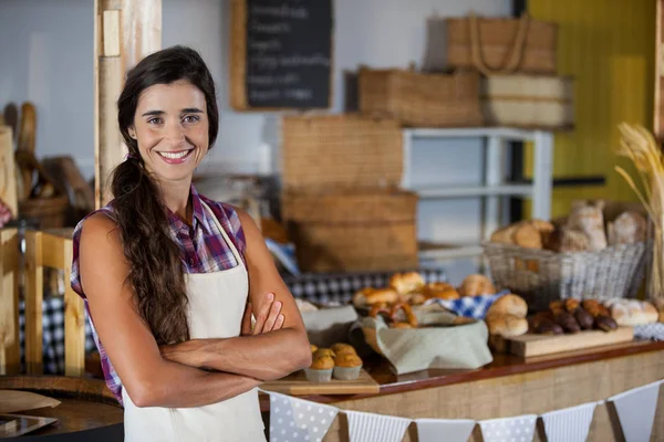 Портрет улыбающейся женщины, стоящей со скрещенными руками в пекарне — стоковое фото