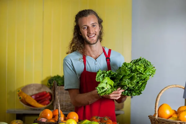 微笑持有绿叶蔬菜市场柜台的工作人员 — 图库照片