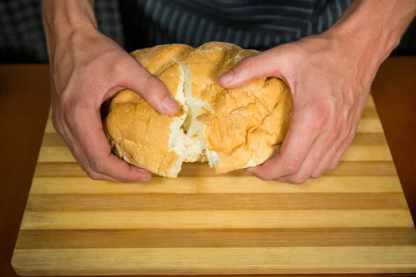 Männliche Angestellte zerreißt Brötchen in Bäckerei — Stockfoto