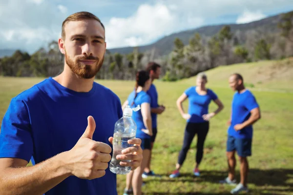Fit man showing thumbs up while holding water bottle — Stock Photo, Image
