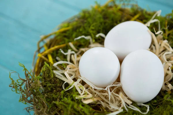 Huevos blancos en el nido en la superficie de madera — Foto de Stock