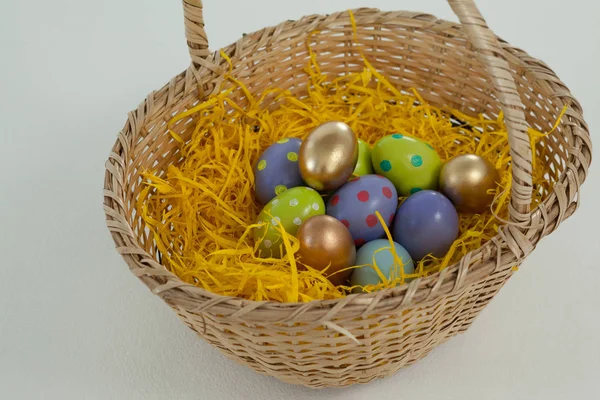 Various Easter eggs in wicker basket — Stock Photo, Image