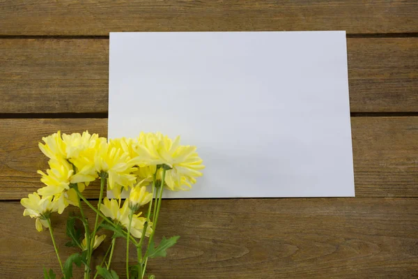 Fiori gialli con busta su tavola di legno — Foto Stock