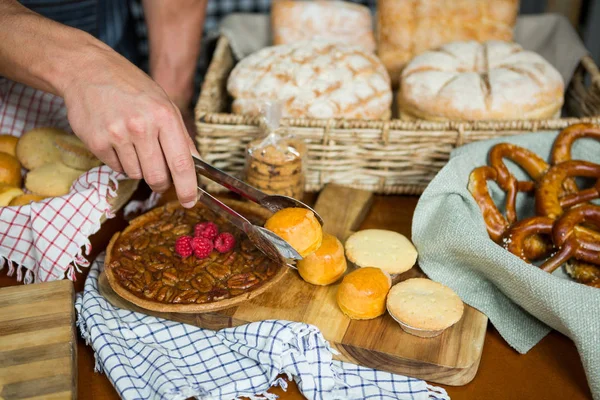 Staff holding cookies with tong in bakery shop — Stock Photo, Image