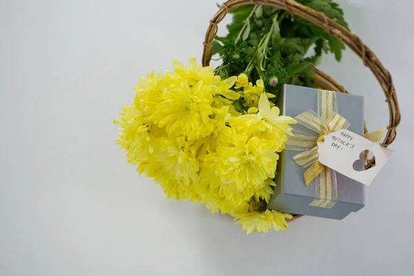 Κουτί δώρου και μάτσο κίτρινα λουλούδια σε ψάθινο καλάθι με ετικέτα ημέρα ευτυχισμένη μητέρες — Φωτογραφία Αρχείου