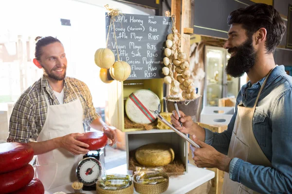 Salesman writing on clipboard at counter in grocery shop — Stock Photo, Image