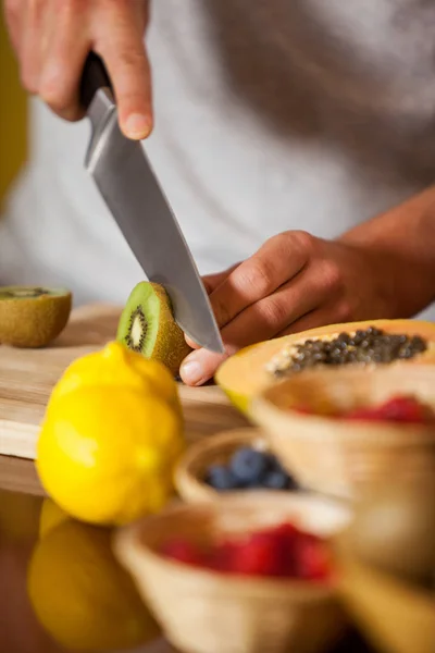 Mid-section of male staff cutting kiwifruit at organic section — Stock Photo, Image