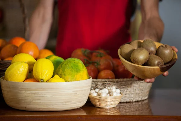 Staff holding a bowl of kiwi at counter in market — Stock Photo, Image