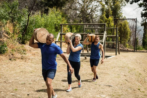 Mensen die zware houten logboeken tijdens hindernissenparcours — Stockfoto