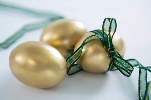 Złote jaja wielkanocne, przewiązane wstążką na białym tle — Zdjęcie stockowe