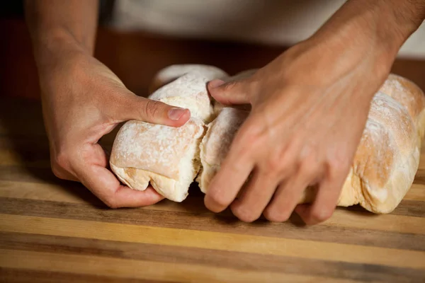 Mannelijke personeel scheuren van een broodje in bakkerij winkel — Stockfoto