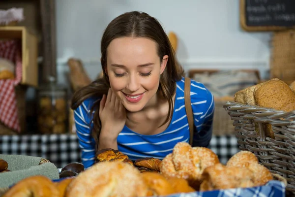 Lächelnde Frau, die am Tresen ein Brot riecht — Stockfoto