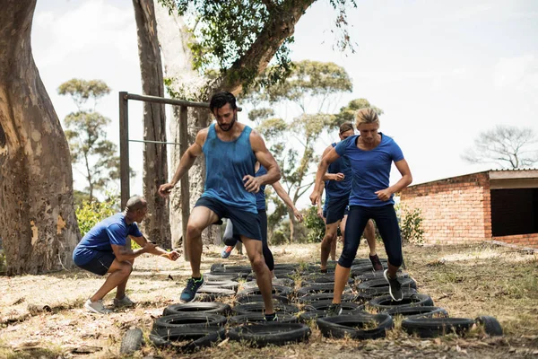 Personas que reciben formación en carrera de obstáculos neumáticos —  Fotos de Stock