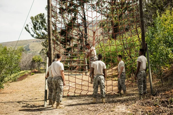 Military soldier climbing rope during obstacle course — Stock Photo, Image