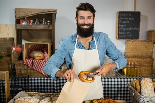 Retrato del pretzel masculino del embalaje del personal en la bolsa de papel — Foto de Stock