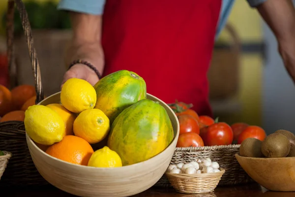 Staff holding a bowl of fruits at counter in market — Stock Photo, Image