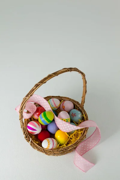 Various Easter eggs with ribbon in wicker basket — Stock Photo, Image