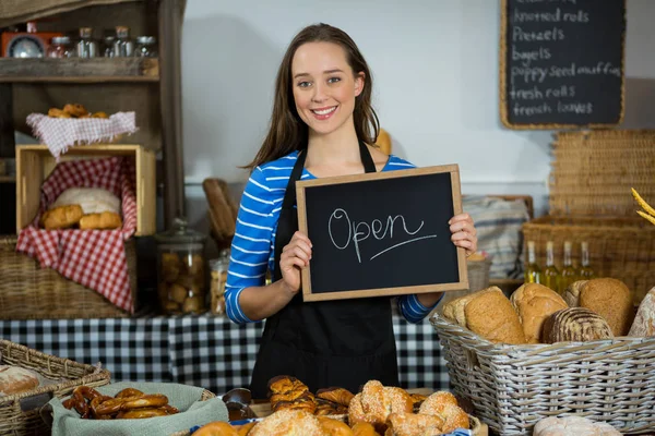 Portrait d'une employée souriante tenant un tableau noir avec panneau ouvert au comptoir — Photo