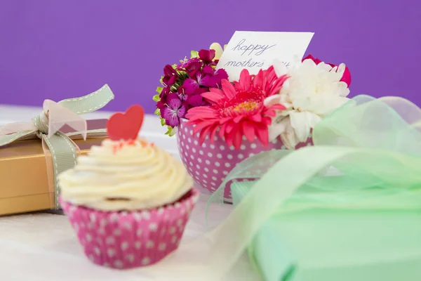 Cup cake, pudełko i świeże kwiaty na powierzchni drewnianych — Zdjęcie stockowe
