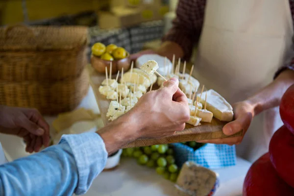 Personal que muestra una muestra de queso al cliente en el mostrador —  Fotos de Stock