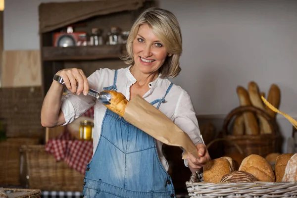 Female staff packing sweet food in paper bag — Stock Photo, Image