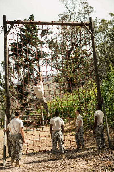 Military soldier climbing rope during obstacle course — Stock Photo, Image