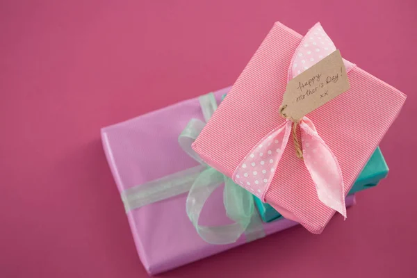 Scatole regalo con felice tag giorno madre sullo sfondo rosa — Foto Stock