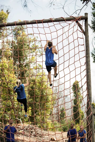 Personas escalando una red durante la carrera de obstáculos — Foto de Stock