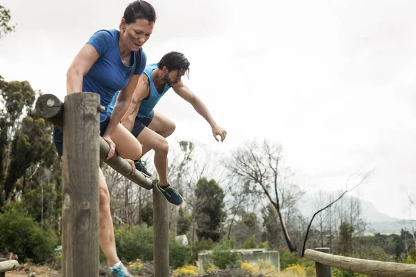 Couple jumping over the hurdles during obstacle course — Stock Photo, Image