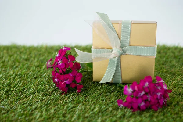 Gift box with flowers on grass — Stock Photo, Image