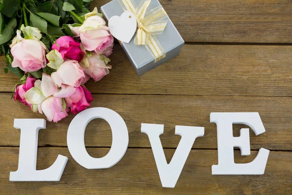 Caja de regalo con ramo de rosas y alfabeto de amor en tablón de madera — Foto de Stock