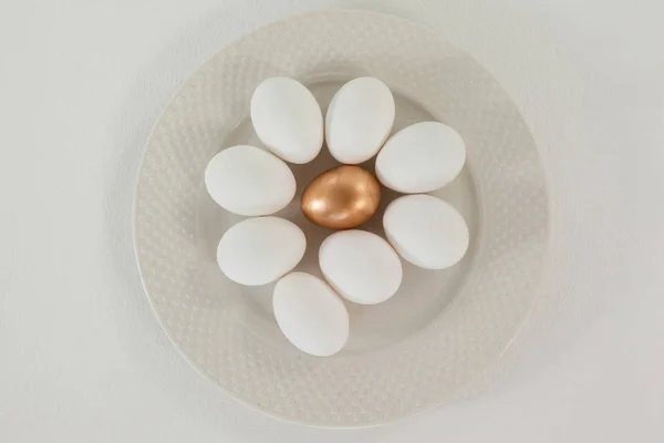 Белые и золотые пасхальные яйца в тарелке — стоковое фото