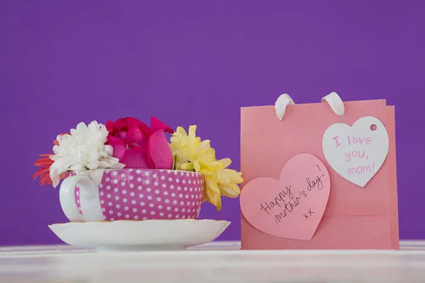 Primer plano de la bolsa de papel con mensaje y flores frescas — Foto de Stock