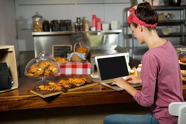 Vrouw met laptop bij bakkerij balie — Stockfoto