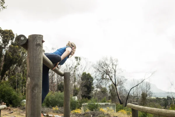 Mujer saltando sobre los obstáculos durante la carrera de obstáculos — Foto de Stock