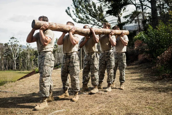 Soldaten, die einen Baumstamm tragen — Stockfoto