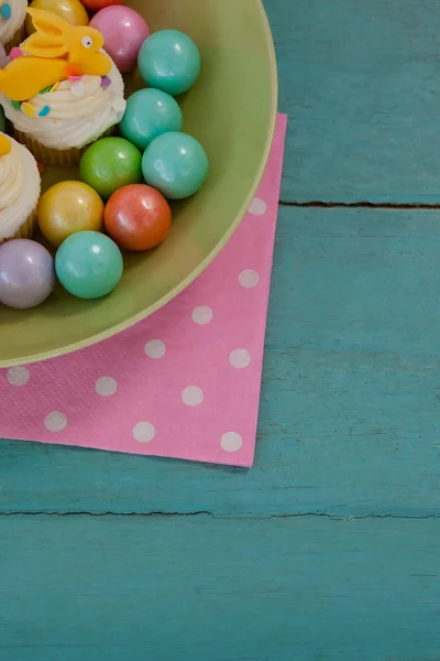 Colorful chocolates and cupcakes in bowl — Stock Photo, Image