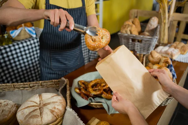 Mid sectie vanpersoneel croissant verpakking in papieren zak aan balie — Stockfoto