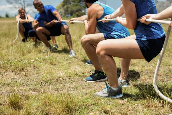 Mensen spelen touwtrekken tijdens opleiding hindernissenparcours — Stockfoto