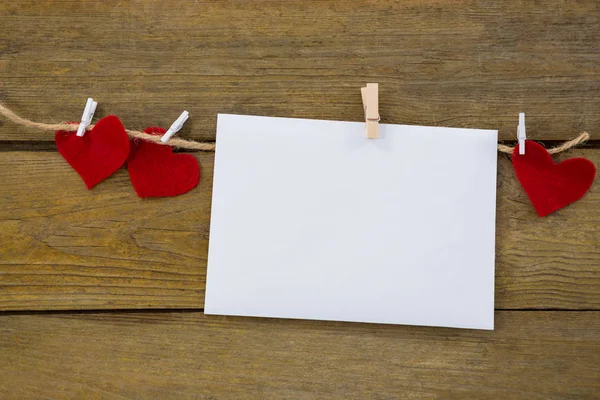 Red hearts and envelope with cloth peg hanging on rope — Stock Photo, Image
