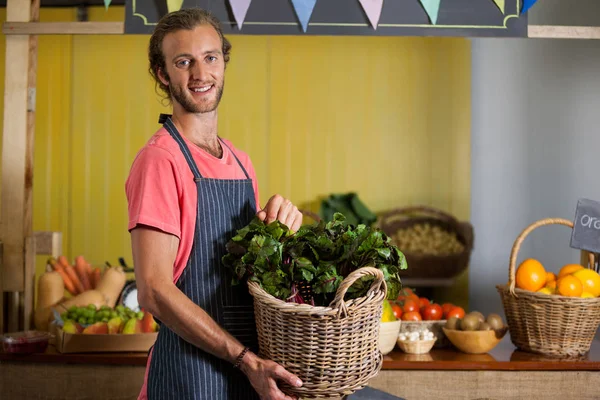 Personnel souriant tenant des légumes feuillus dans le panier à la section biologique — Photo