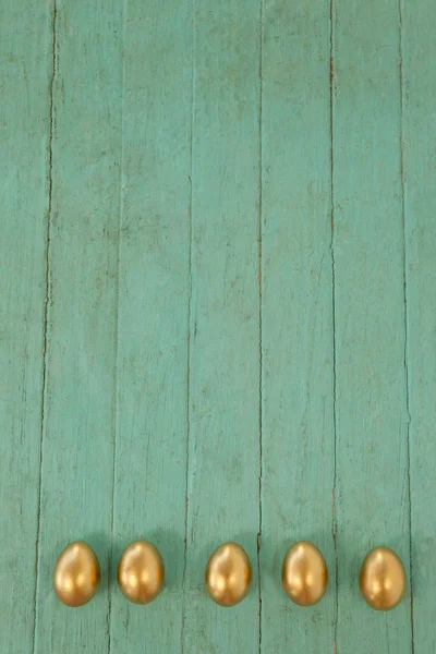 Gouden paaseieren gerangschikt op houten oppervlak — Stockfoto