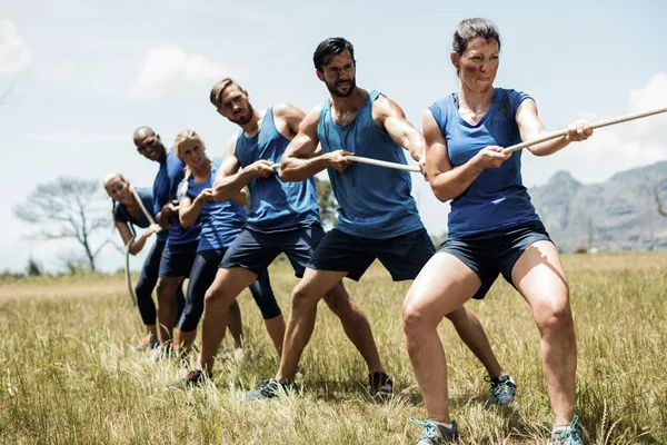 Mensen spelen touwtrekken tijdens opleiding hindernissenparcours — Stockfoto