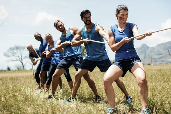 Gente jugando tira y afloja durante el curso de entrenamiento de obstáculos —  Fotos de Stock