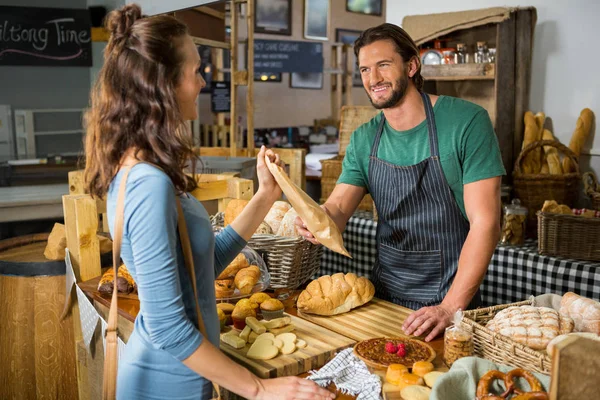 Lächelnde Kundin, die am Schalter ein Paket vom Bäckereipersonal entgegennimmt — Stockfoto