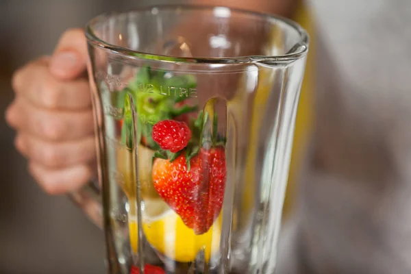 Männliche Mitarbeiter halten Saftmixer mit verschiedenen Früchten in der Hand — Stockfoto